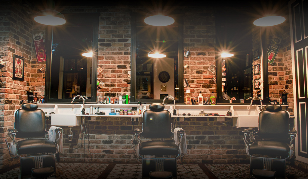 Barbershop interior with three barber chairs and mirrors against a brick wall